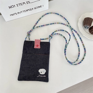 Detail of denim crossbody bag featuring dog embroidery and colorful beaded strap