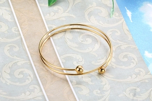 Close-up of double-layered gold stainless steel cuff bracelet with polished bead ends