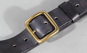 Macro detail of vintage brass buckle and high-quality black genuine leather belt texture