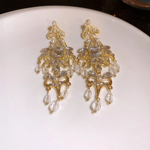 Close-up of vintage flower earrings with gold finish, crystals, and pearl tassels