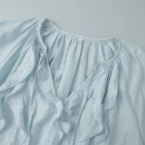 Detailed view of light blue shirt featuring ruffle trim and textured crinkle fabric
