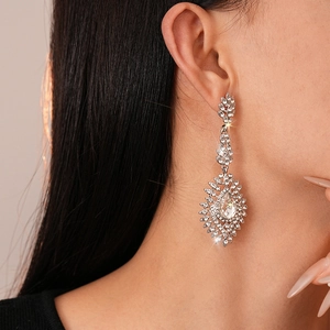 Détail des boucles d'oreilles pendantes argentées avec strass fleuris portées