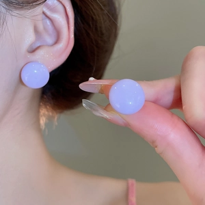 Macro shot of minimalist lavender purple ball stud earrings worn on ear and held by hand