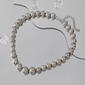 Detail of silver beaded necklace with adjustable lobster clasp on reflective mirror