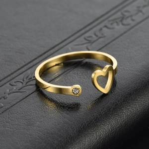 Golden heart-shaped open ring with a small diamond accent on a black leather background