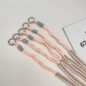 Detail of hand-woven pink and gray crossbody strap with silver metal ring buckles