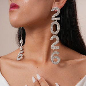 Macro view of long silver 2026 number earrings with shimmering rhinestones on a model