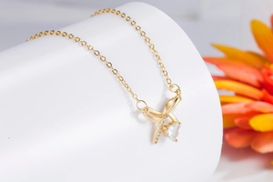 Close-up of golden bow necklace with heart-shaped crystal pendant and small zircon stones