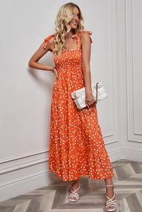 Close-up of the orange polka dot dress showing tie-up shoulder straps and smocked bodice