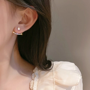 Close-up of elegant gold stud earrings with round diamonds and curved pave accents