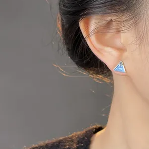 Detail shot of a triangle earring with blue marble pattern on a model's ear