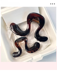 Detail view of two tortoiseshell hair claws in S-curve design inside a white gift box