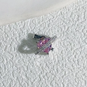 Close-up of pink heart pendant with silver arrow band and clear sparkling zircon stones