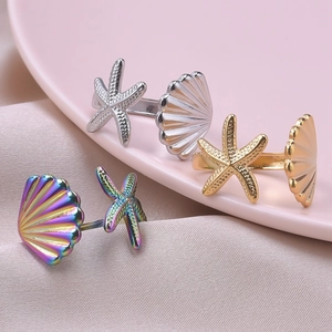 Close-up of starfish and seashell open rings in silver, gold, and rainbow finishes