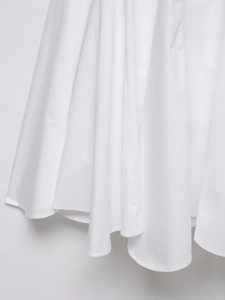 Gros plan détaillé de l'ourlet de robe midi blanche montrant la texture du tissu