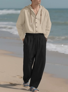 Detailed texture of men's beige linen hooded shirt and black drawstring beach trousers set