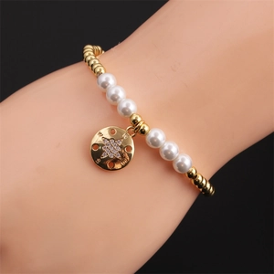 Détail d'un bracelet de perles dorées et nacrées avec pendentif boussole au poignet