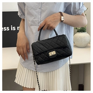 Detail of black quilted leather handbag with gold chain strap and square metal lock