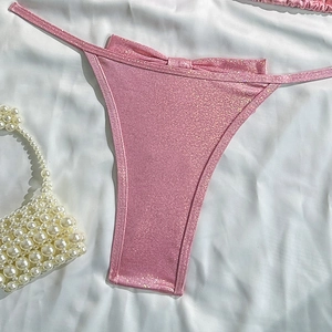 Detailed close-up of pink glitter bikini bottoms on elegant white silk background