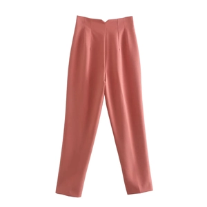 Detail of coral pink high-waisted tailored trousers with front pleats and smooth fabric