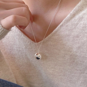 Close-up of a minimalist 925 sterling silver ball pendant necklace worn on a model