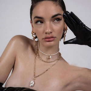 Boucles d'oreilles dorées et colliers superposés avec perles baroques sur un mannequin