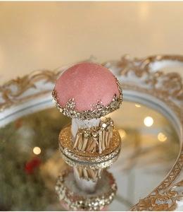 Close-up of pink glitter mushroom ornament with gold sequins on a reflective mirror tray