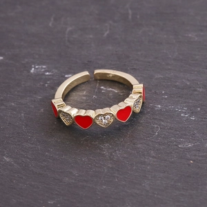 Detail of gold heart open ring featuring red enamel and sparkling zircon pavé heart charms