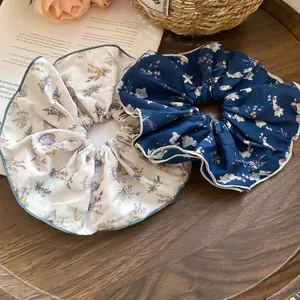 Floral and rabbit print fabric scrunchies in cream and navy blue on a wooden tray