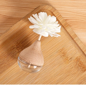Detail view of flower-shaped diffuser sticks in glass bottle on a wooden tray