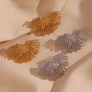 Macro shot of 18K gold and silver sunburst fan earrings on satin background