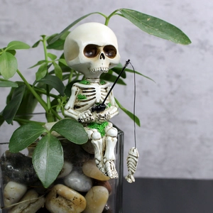Macro view of a resin fishing skeleton figurine with moss details sitting on a glass vase