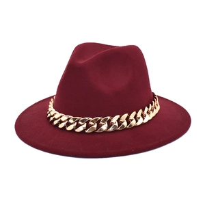 Detailed close-up of burgundy fedora hat with chunky gold chain decoration
