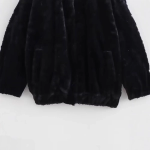 Faux fur bomber jacket in black with detailed view of ribbed hem and plush texture