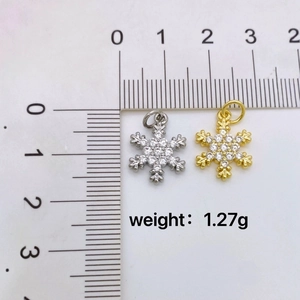 Gold and silver snowflake pendants with zircon inlays and scale for size measurement