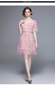 Détail d'une robe en dentelle rose clair avec manches bouffantes et col carré chic