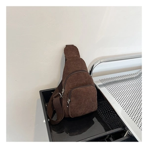 Detailansicht der dunkelbraunen Cord-Struktur und silbernen Reißverschlüsse der Brusttasche