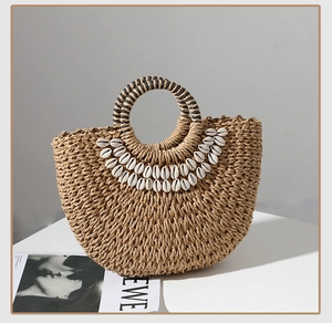 Detailed view of handmade woven straw bag featuring real seashells and striped round handles