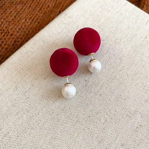 Détail des boucles d'oreilles double boule en velours rouge et perle blanche