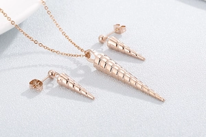 Macro shot of rose gold conical spiral necklace and stud earrings set on a white surface