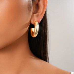 Close-up of elegant gold C-shaped hoop earring worn by a model with a polished finish