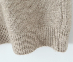 Close-up of beige knitted fabric showing textured ribbed cuff details and soft weave