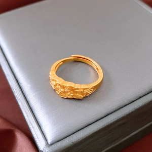 Détail de la bague croix plaquée or avec relief floral sur une boîte à bijoux en soie
