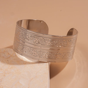 Detailed macro view of the wide silver metal open cuff bracelet with embossed butterfly patterns