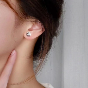 Elegant silver four-leaf clover stud earring with sparkling zircon shown on ear