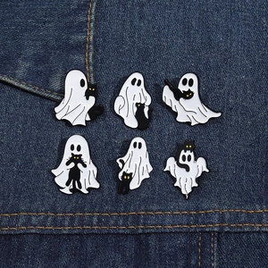 Detail of six ghost and black cat enamel pins on blue denim fabric for Halloween