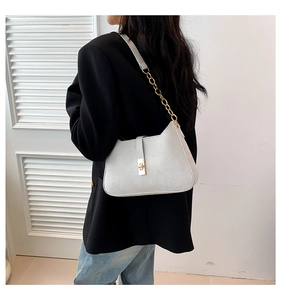 Close-up of white suede shoulder bag featuring a gold chain strap and metal lock detail