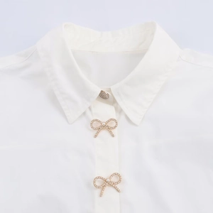 Elegant white poplin shirt featuring decorative pearl and rhinestone bow buttons detail