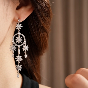 Close-up of silver tassel earrings with zircon stars worn by a model in soft lighting