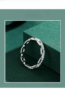 Dettaglio macro di anello geometrico in argento S925 con cristalli su supporto verde